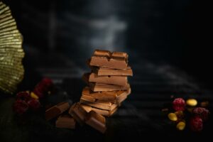 Tempting stack of chocolate pieces accompanied by berries and nuts, perfect for food photography.